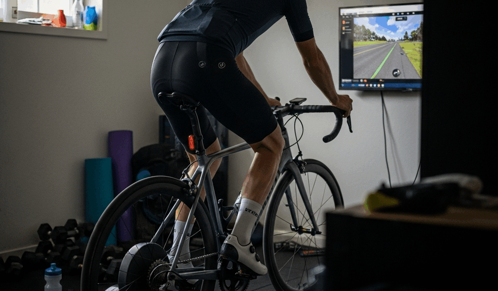 cyclist on smart trainer in home gym setup with screen