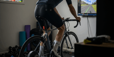 cyclist on smart trainer in home gym setup with screen
